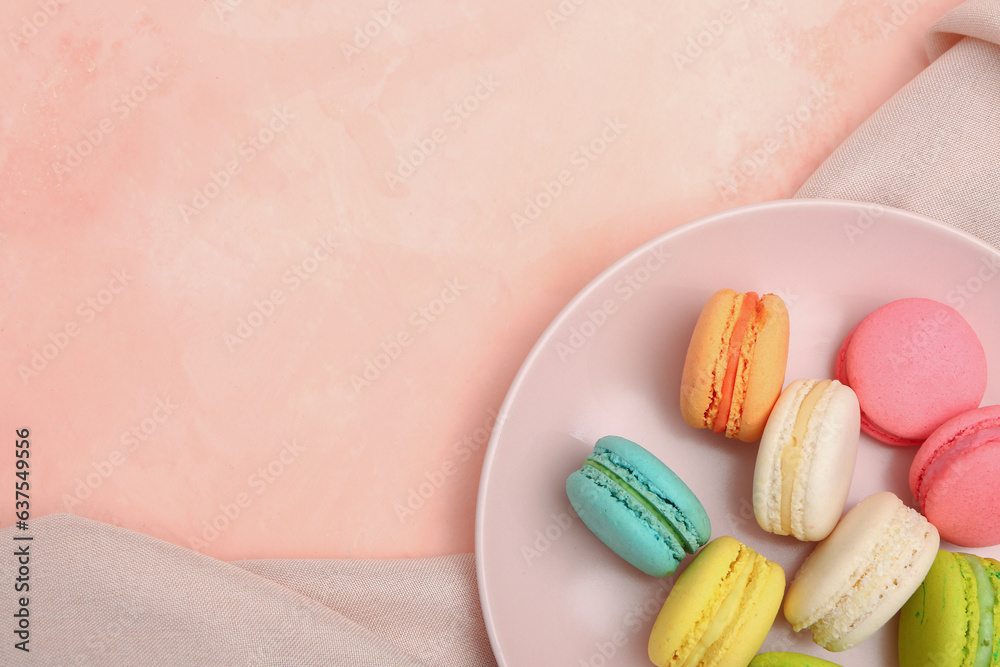 Plate with sweet macaroons on pink background