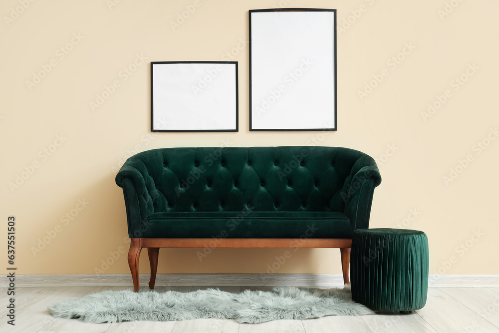 Interior of living room with blank frames, green sofa and pouf