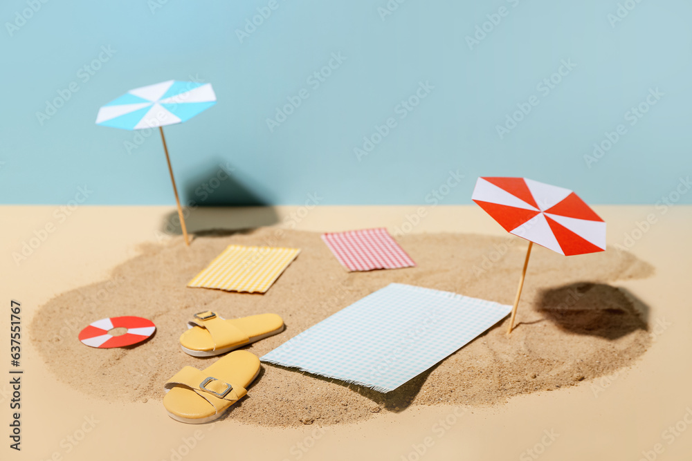 Creative summer composition with mini umbrellas, beach accessories and sand on color background