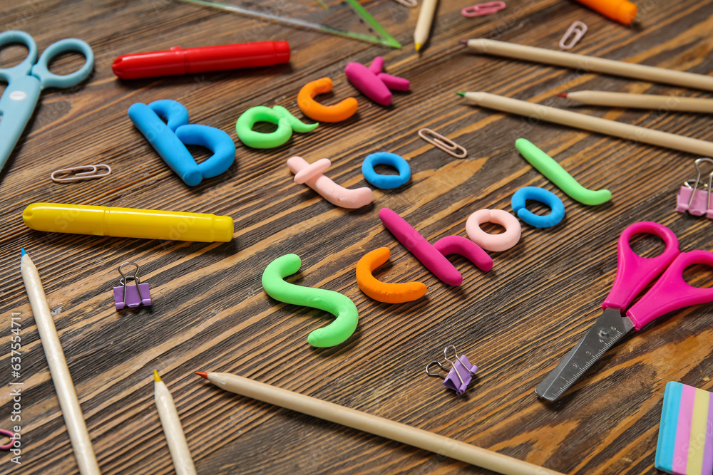 Text BACK TO SCHOOL and stationery on wooden background