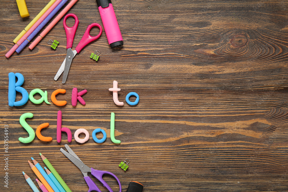 Text BACK TO SCHOOL and stationery on wooden background