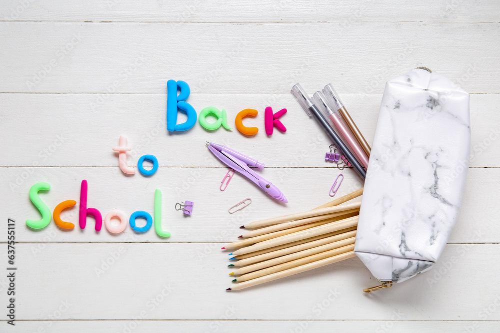 Text BACK TO SCHOOL and stationery on white wooden background