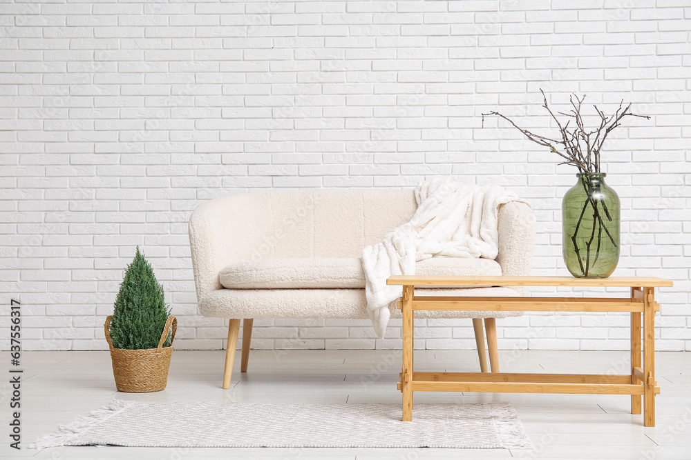 White sofa and vase with tree branches on coffee table in stylish living room