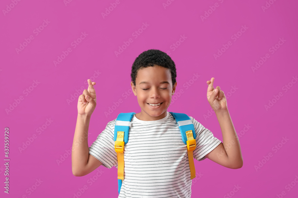 Little African-American schoolboy in stylish uniform on purple background