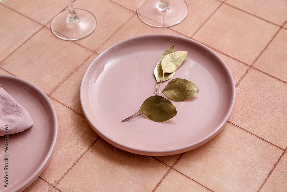 Elegant table setting with golden leaves in pink plate on beige tiled background