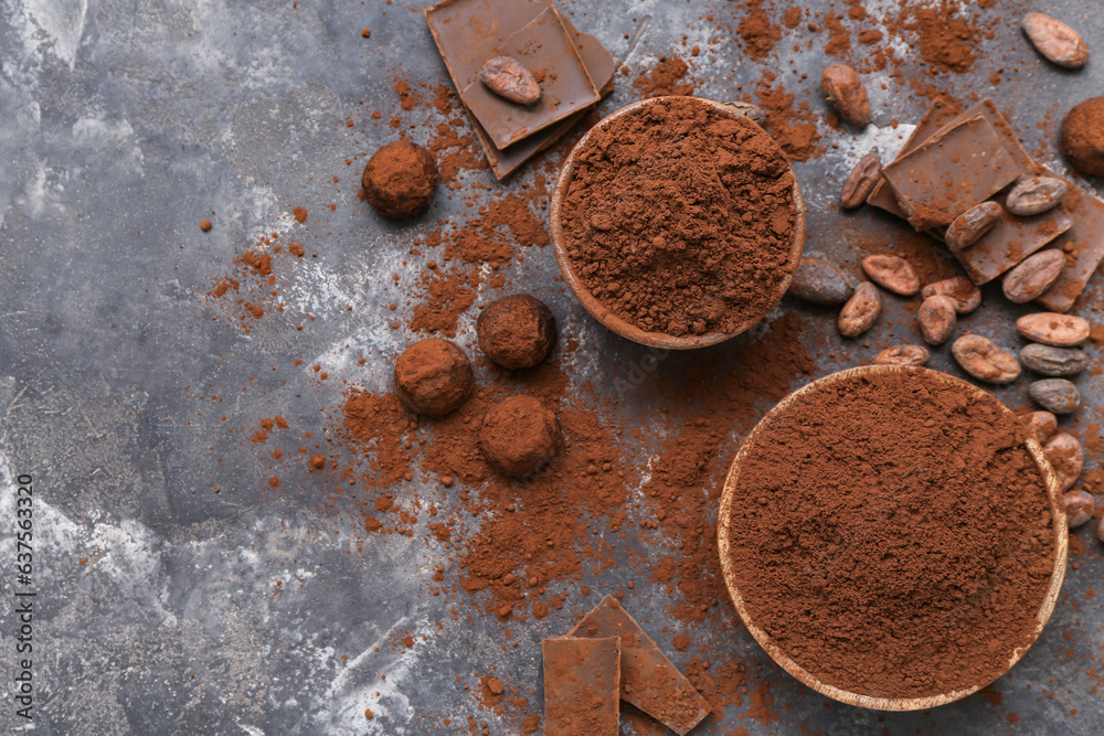 Bowls with cocoa powder, candies, beans and chocolate on black background