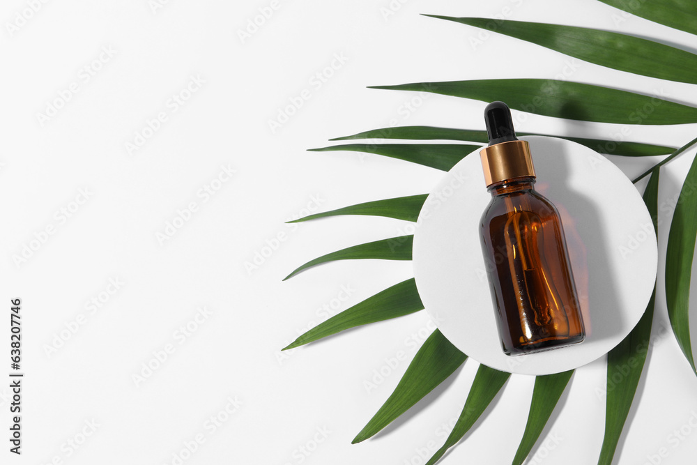 Bottle with cosmetic oil and green leaf on white background, top view. Space for text