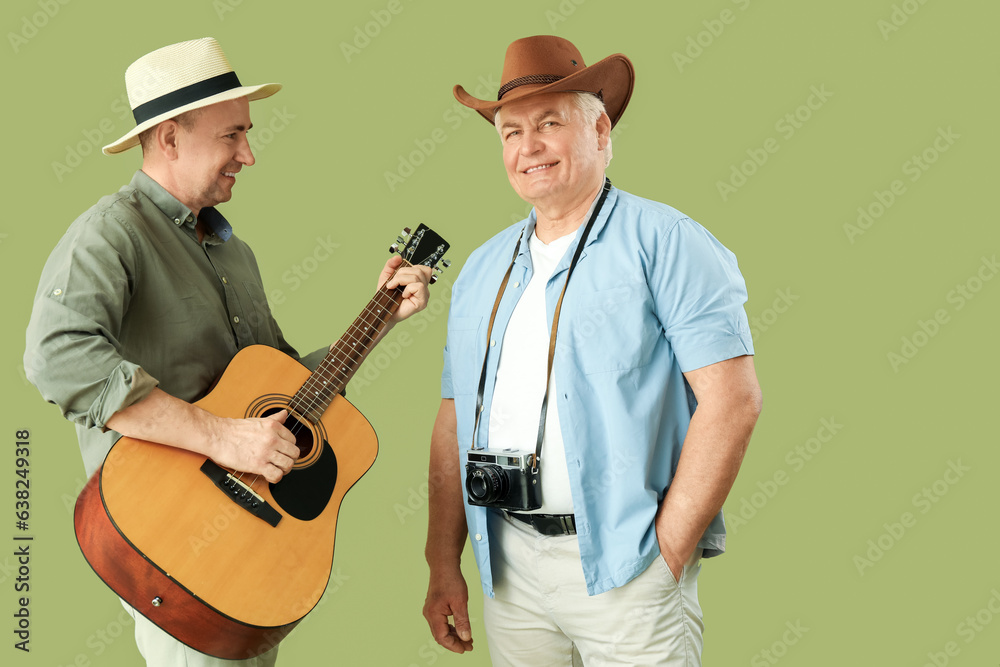 Mature brothers with guitar on green background