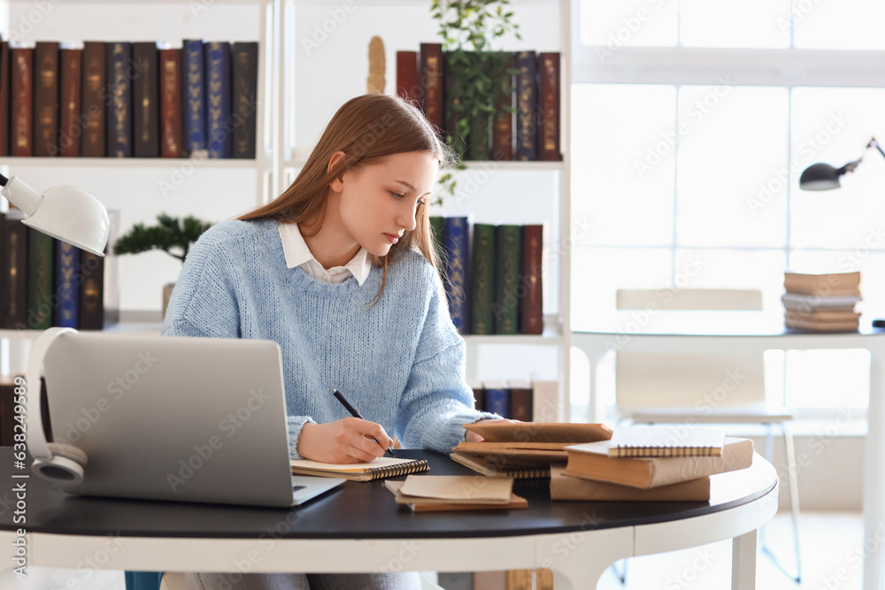 Female student studying at table in library