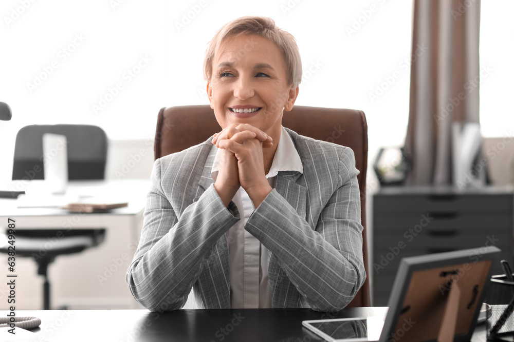 Happy mature businesswoman at workplace in office