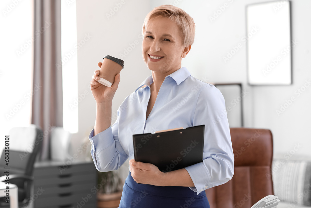 Mature businesswoman with documents and coffee in office