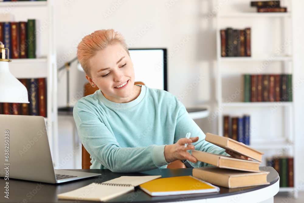 Female student studying with books at table in library