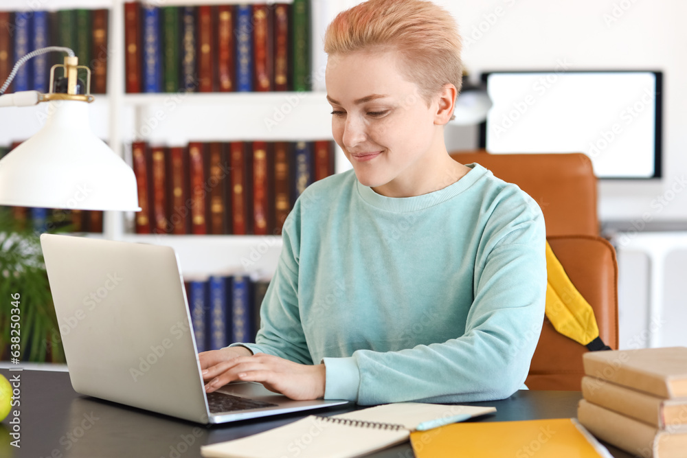 Female student studying with laptop at table in library