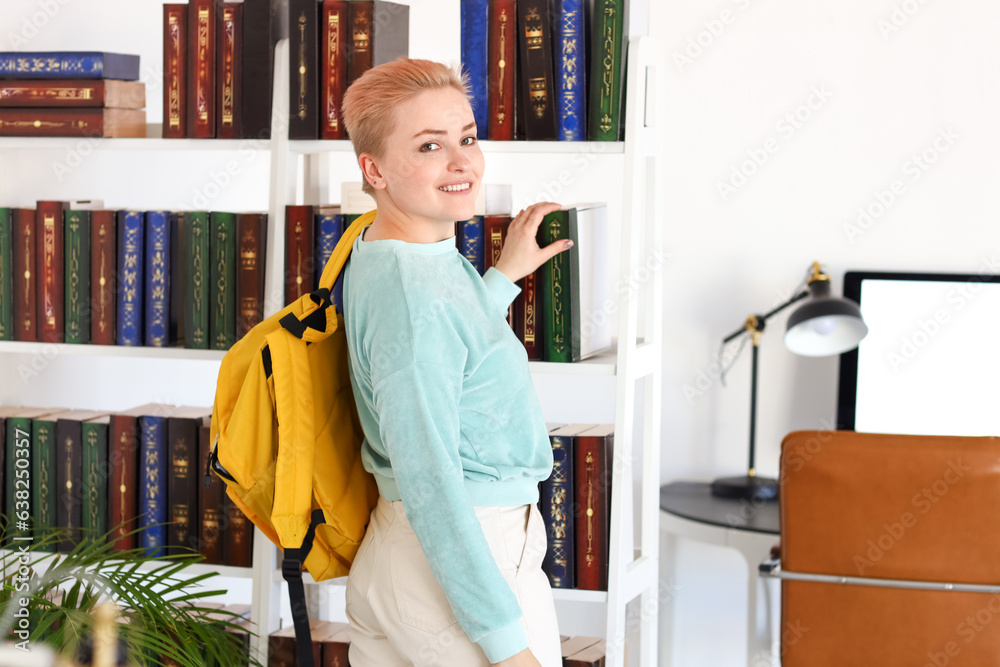 Female student taking book from shelf in library