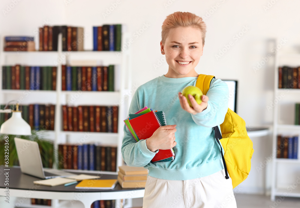 Female student with notebooks and apple in library