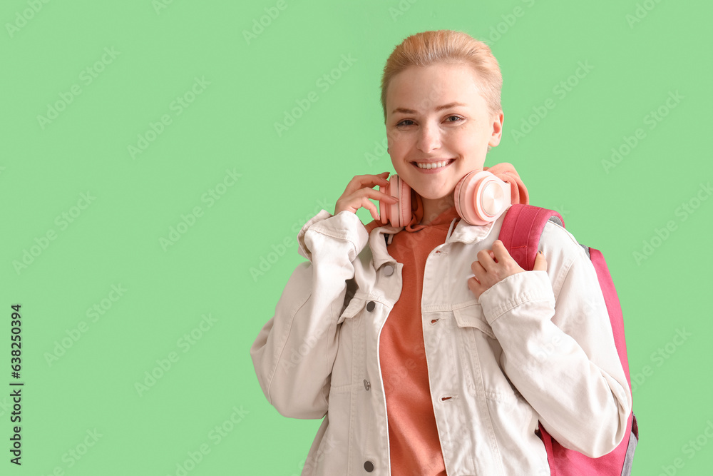 Female student with headphones on green background