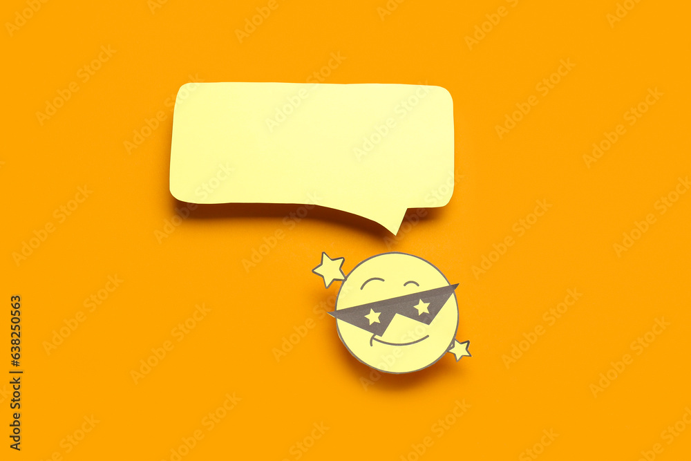 Paper face in sunglasses with blank speech bubble on orange background