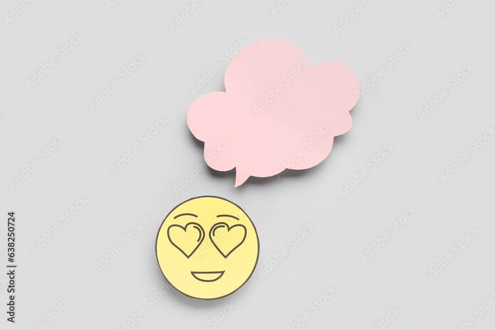 Paper face with heart eyes and blank speech bubble on grey background