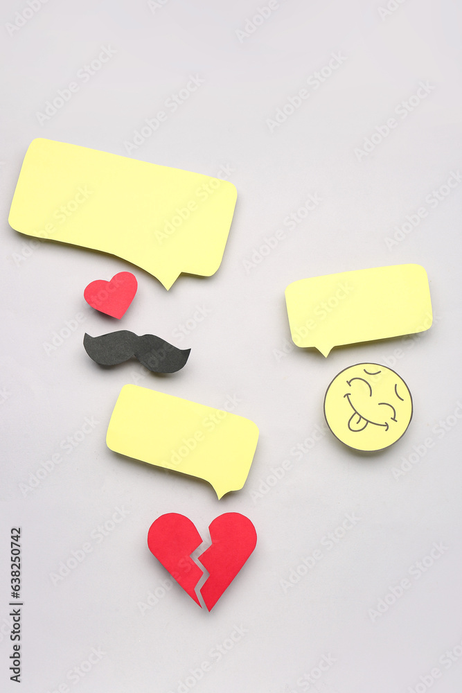 Paper face, mustache and broken heart with speech bubbles on grey background