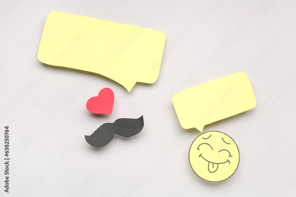 Paper face, mustache and heart with speech bubbles on grey background