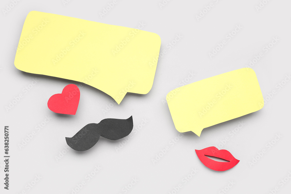 Paper mustache and lips with speech bubbles on grey background