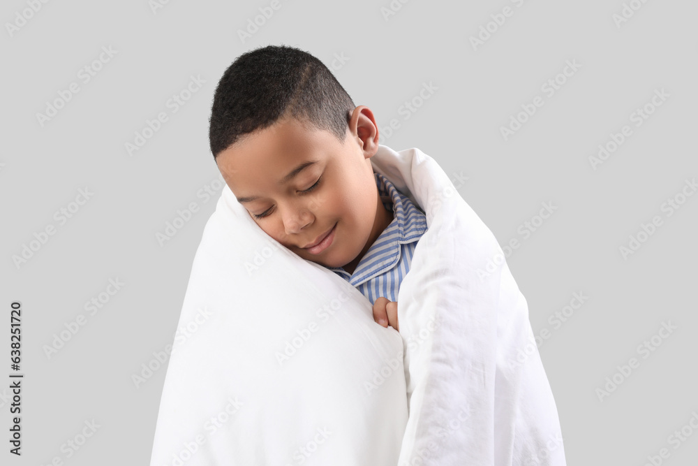 Little African-American boy with soft blanket on light background, closeup