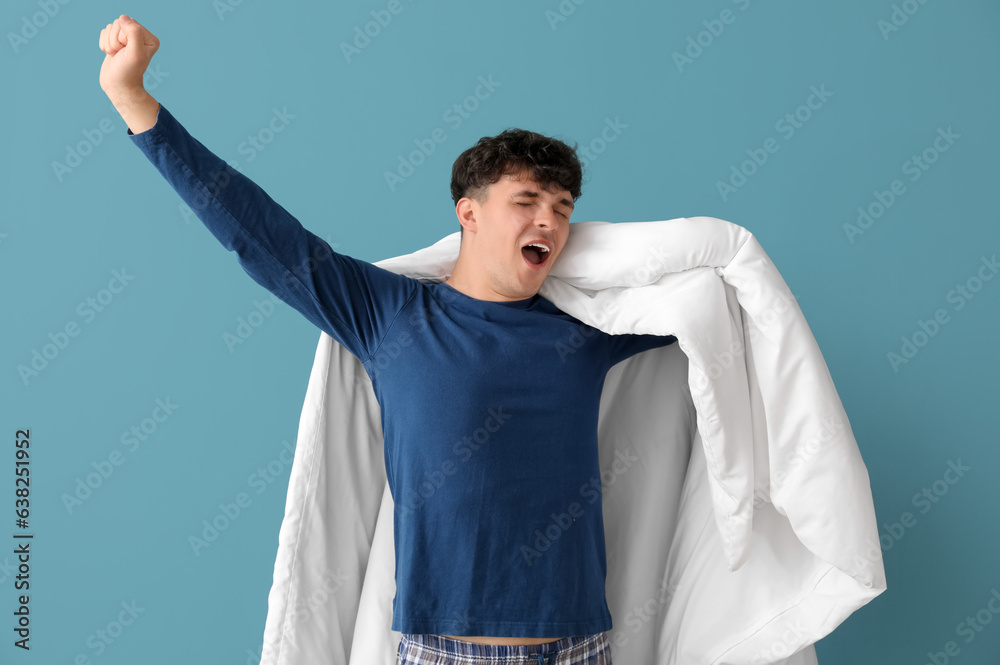 Awaking handsome man with soft blanket on blue background