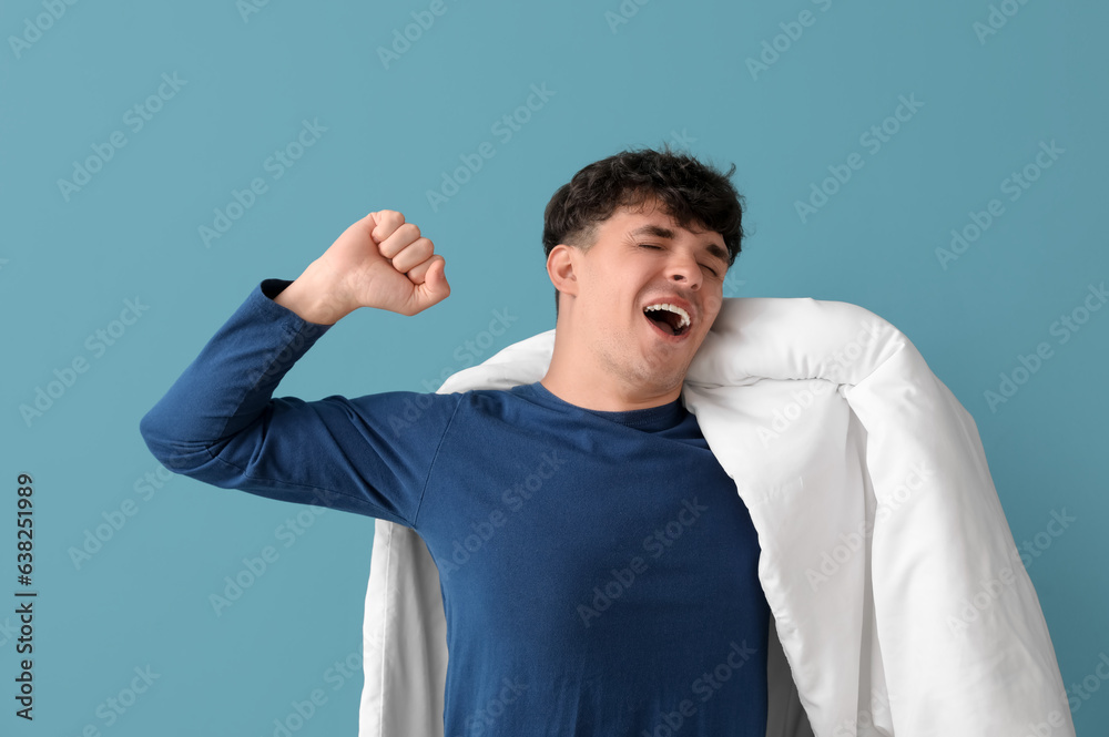 Awaking handsome man with soft blanket on blue background