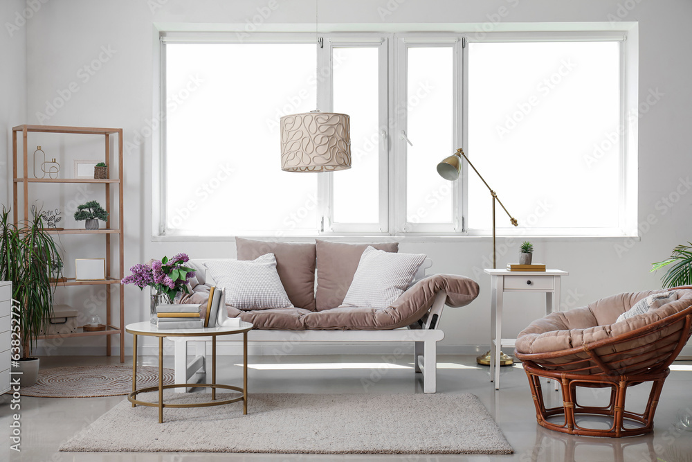 Interior of living room with sofa, armchair and stylish holder for books on coffee table