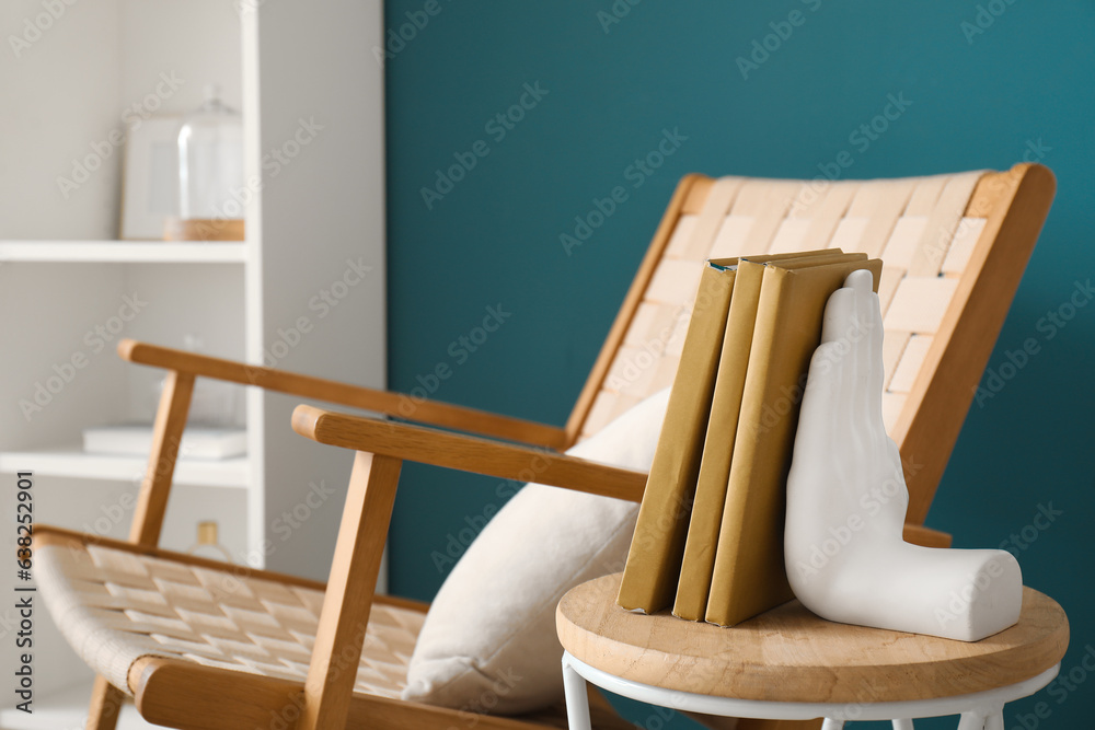 Chair with stylish holder for books on table in room