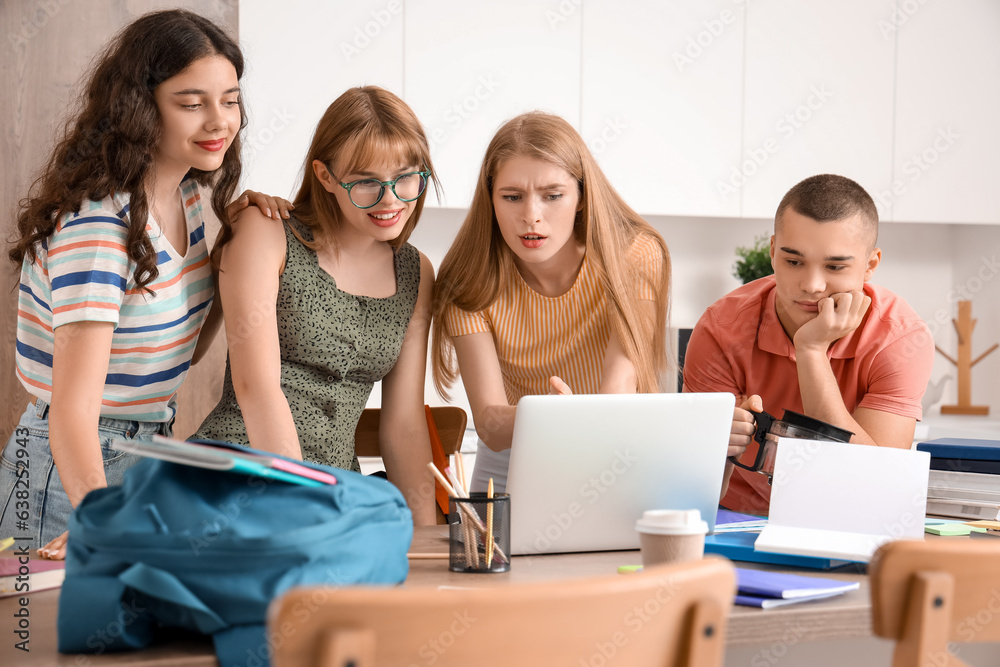 Group of students studying with laptop in kitchen