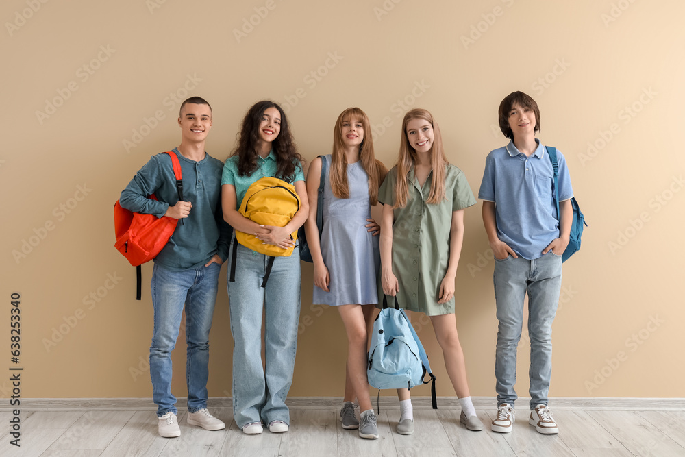 Group of students with backpacks near beige wall