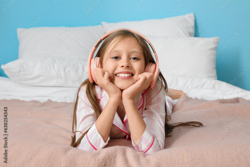 Little girl with headphones in bedroom