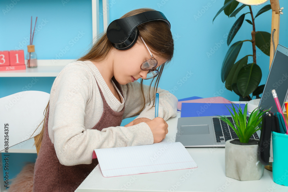 Little girl in headphones studying at home