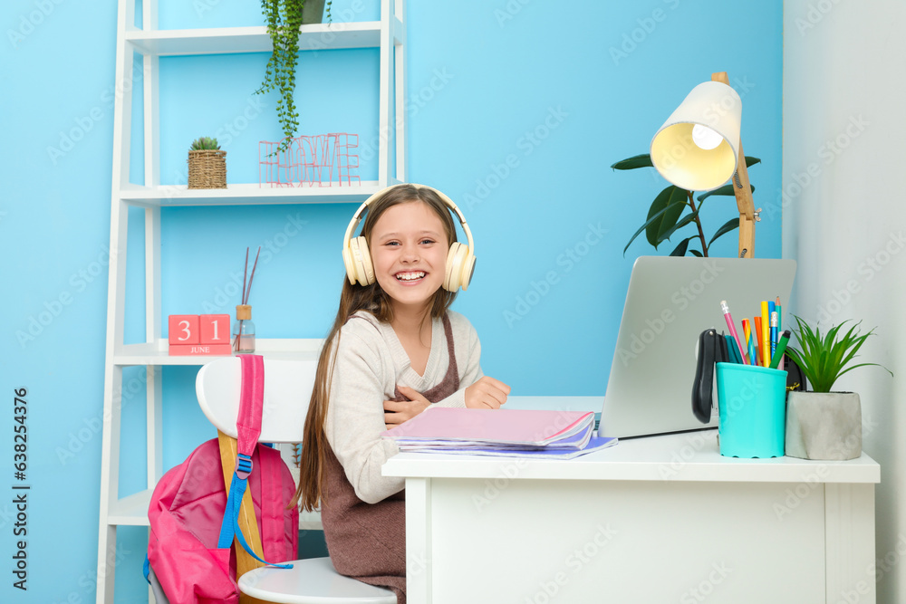 Little girl in headphones studying at home