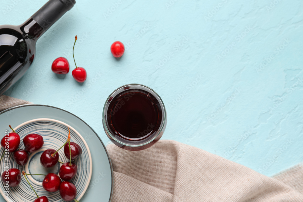 Bottle and glass of sweet cherry liqueur with berries on blue background