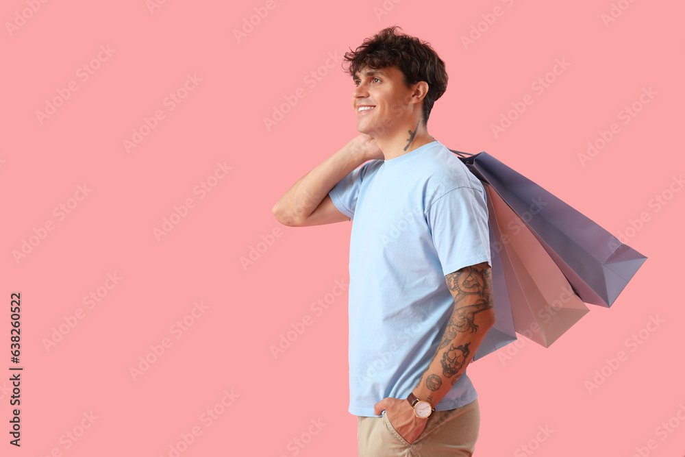 Young man with shopping bags on pink background