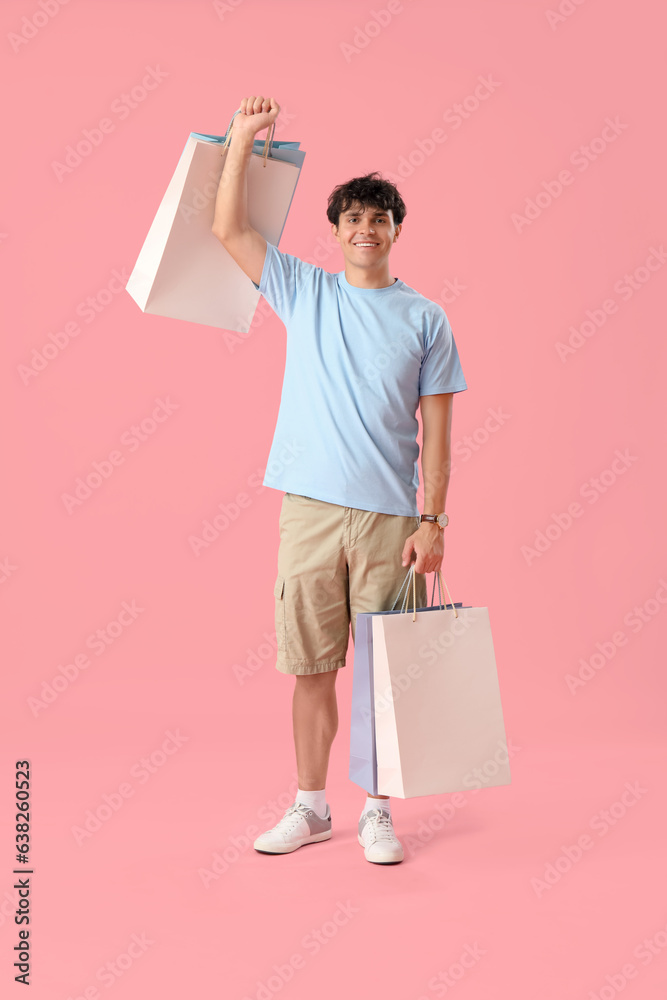 Young man with shopping bags on pink background