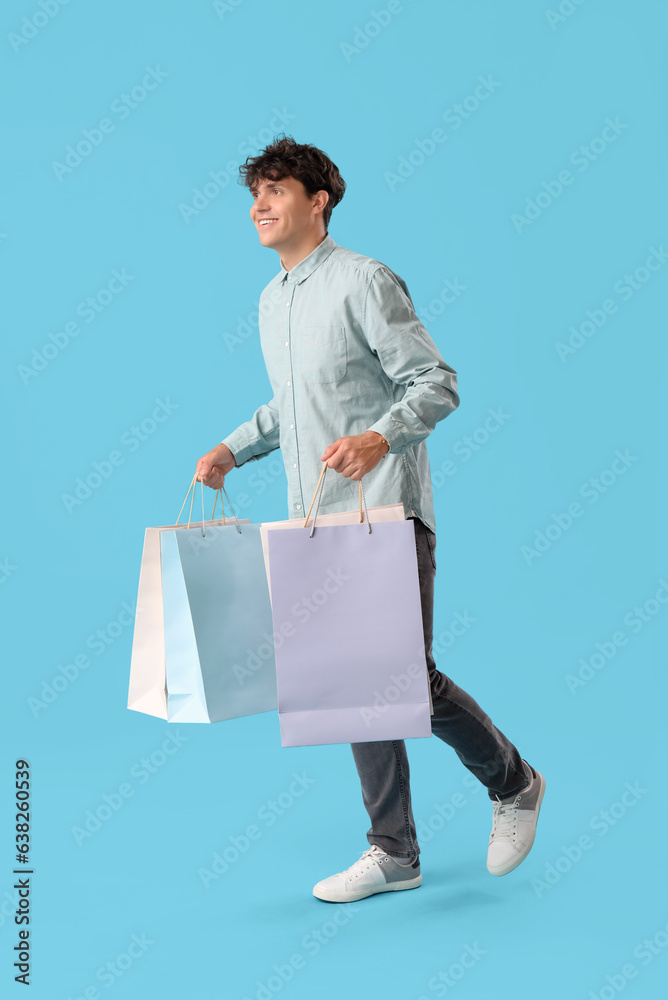 Young man with shopping bags on blue background