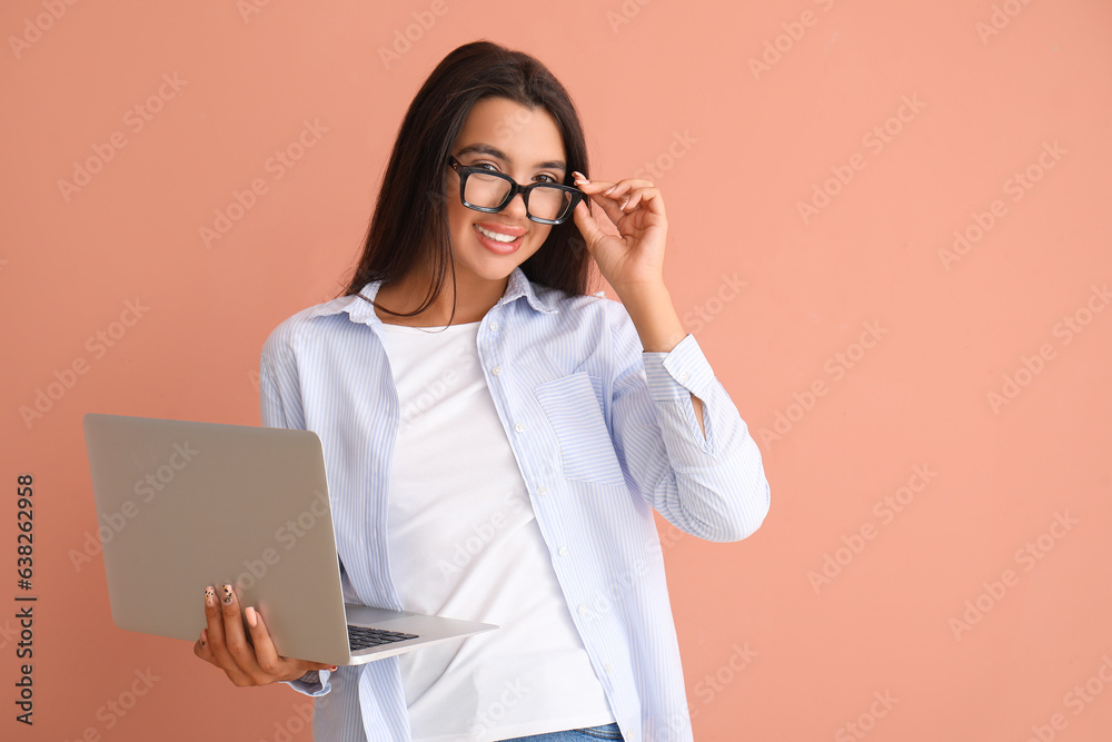 Happy young female programmer with laptop on orange background