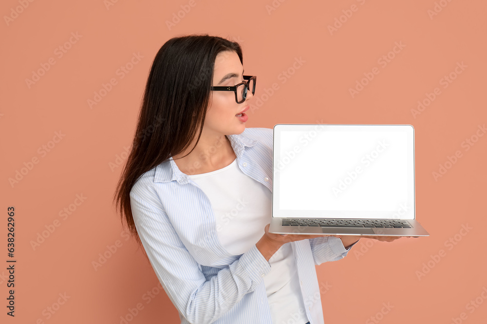 Shocked young female programmer with laptop on orange background