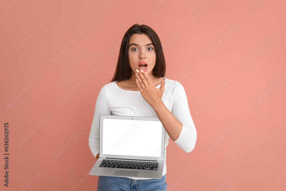 Shocked young female programmer with laptop on orange background