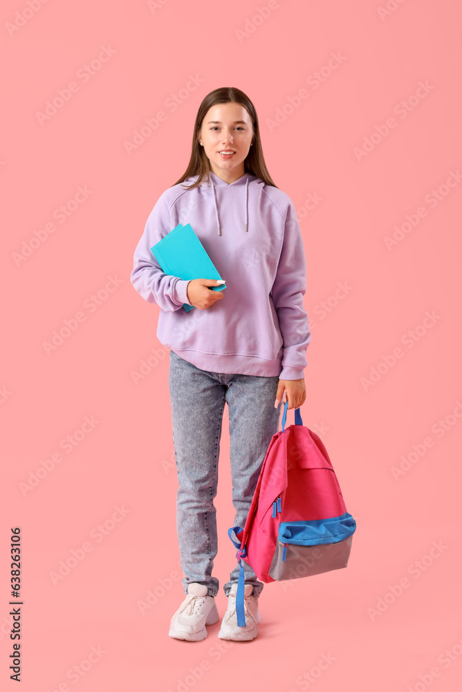 Happy female student with backpack and notebook on pink background