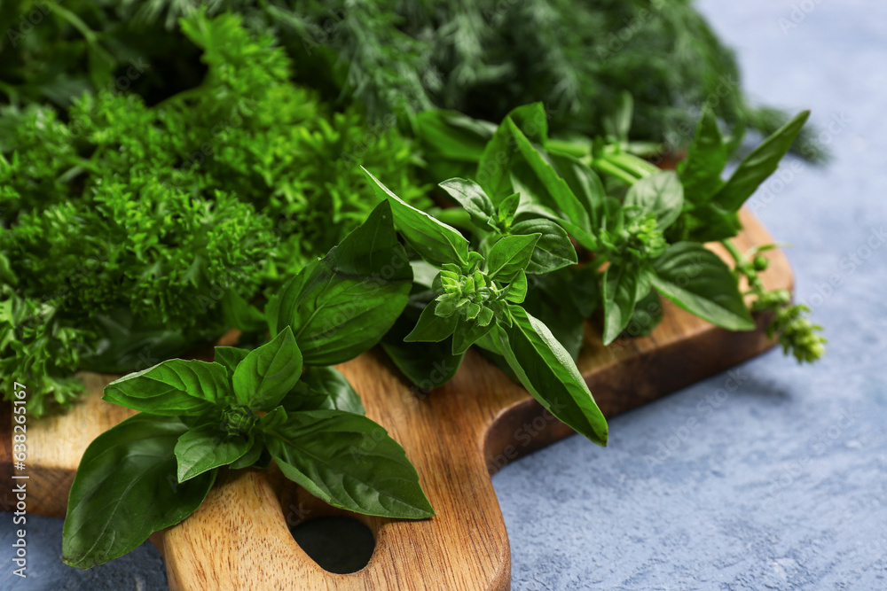 Wooden board with fresh herbs on color background, closeup