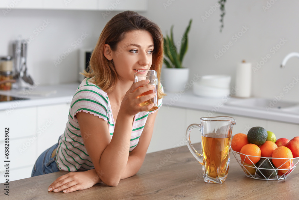 Young woman with glass of juice in kitchen