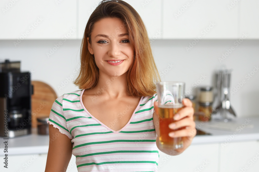 Young woman with glass of juice in kitchen, closeup