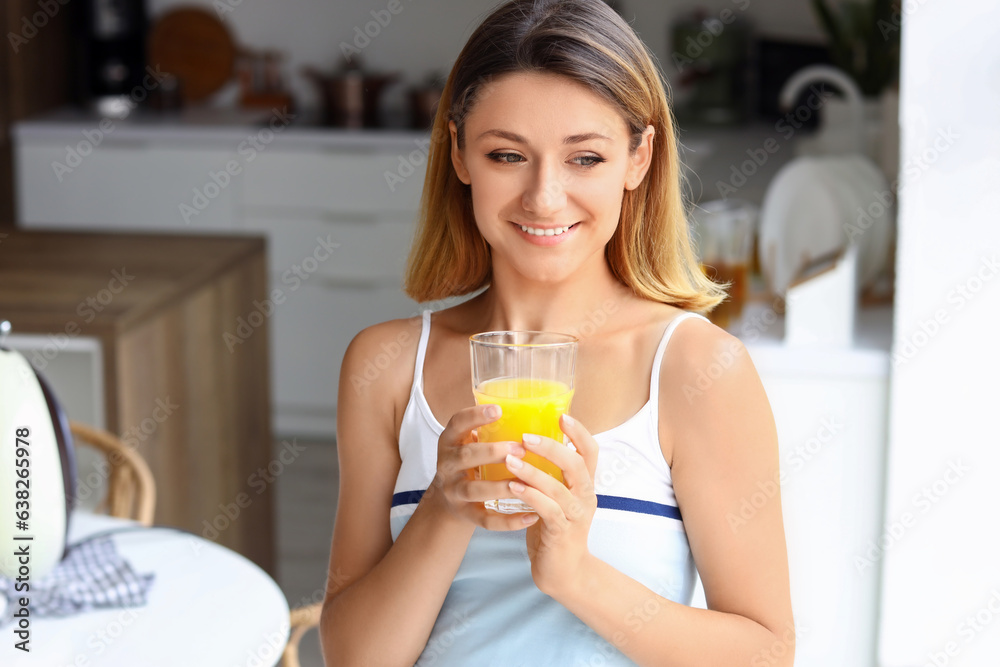 Young woman with glass of juice in kitchen