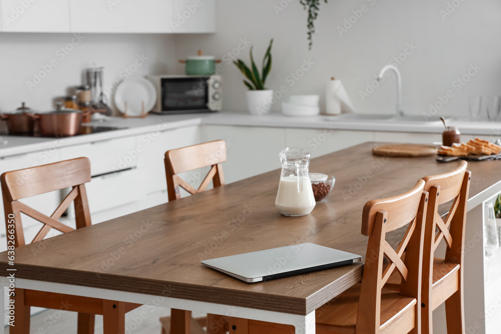 Laptop on dining table in kitchen, closeup