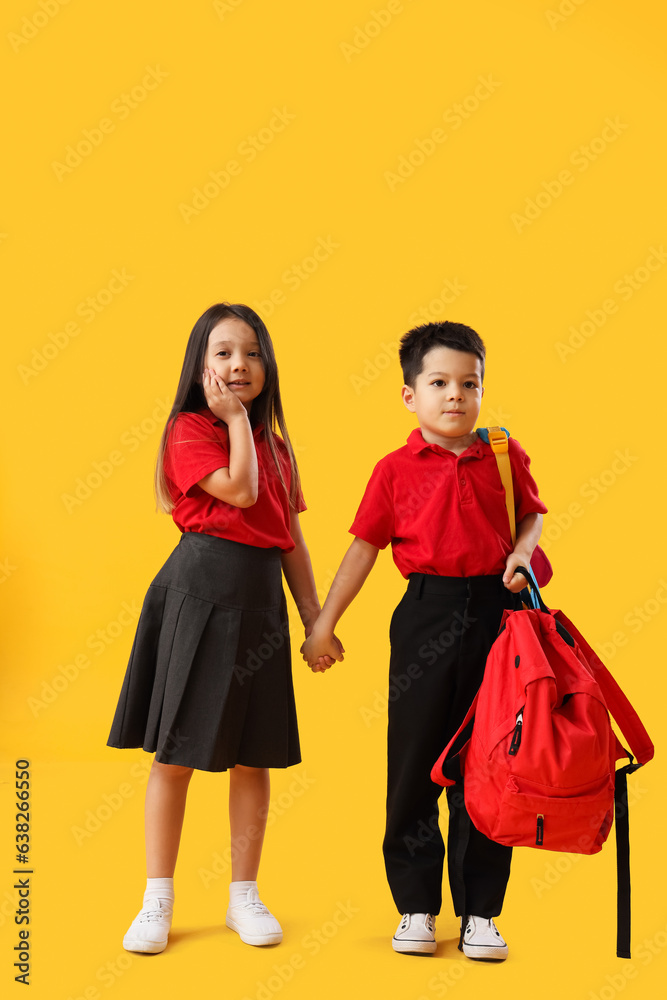 Little school children with backpacks on yellow background