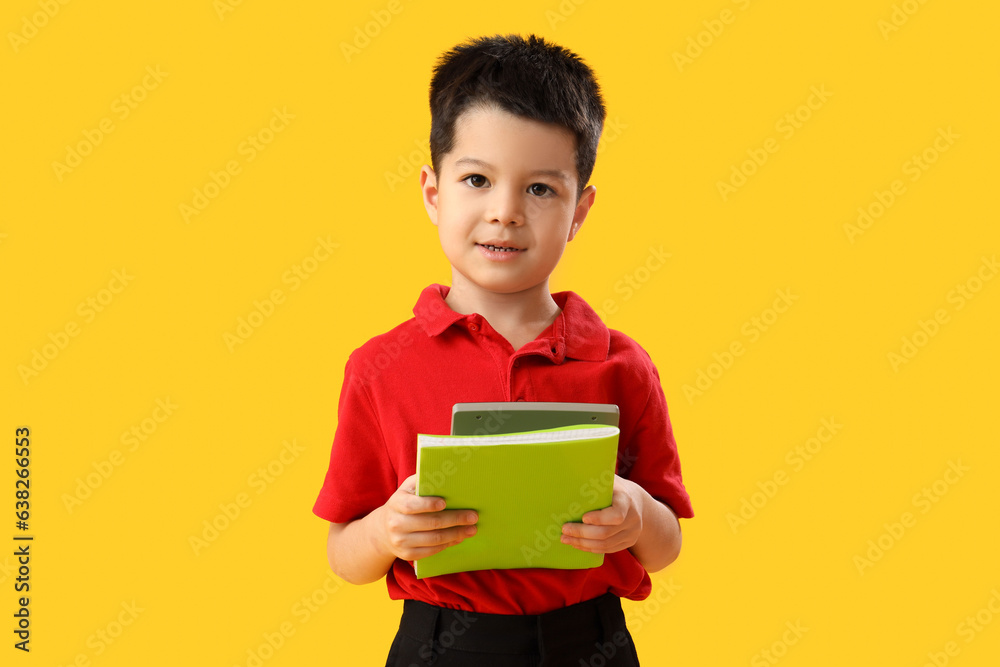 Little school boy with stationery on yellow background